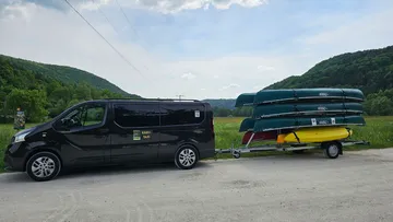 Van towing canoes on trailer in countryside.
