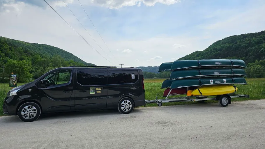 Transporter zieht Kanus auf Anhänger auf dem Land.