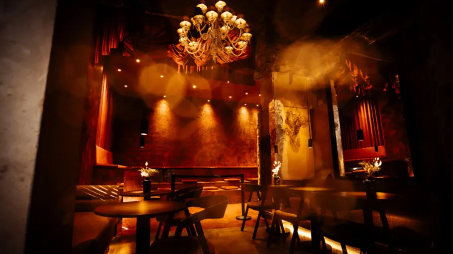 Luxurious dimly-lit lounge with chandelier and tables.