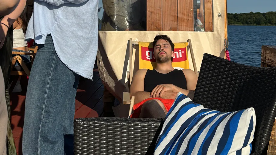 Man sleeping on a deck chair by the water.