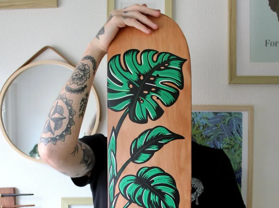 Person hält Skateboard mit Blätterdesign drinnen.