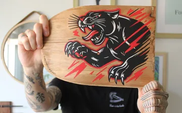 Person holding skateboard with panther design.