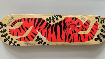 Tiger artwork on wooden skateboard deck.