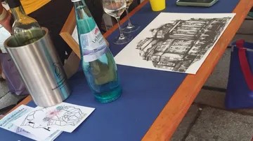 Tisch mit Getränken und Gebäudezeichnung.