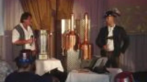 Zwei Männer präsentieren Kupferdestillen auf Bühne.
