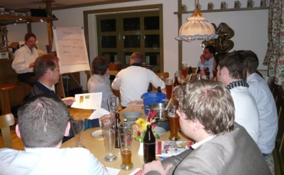 Personen sitzen bei einem Seminar am Tisch.