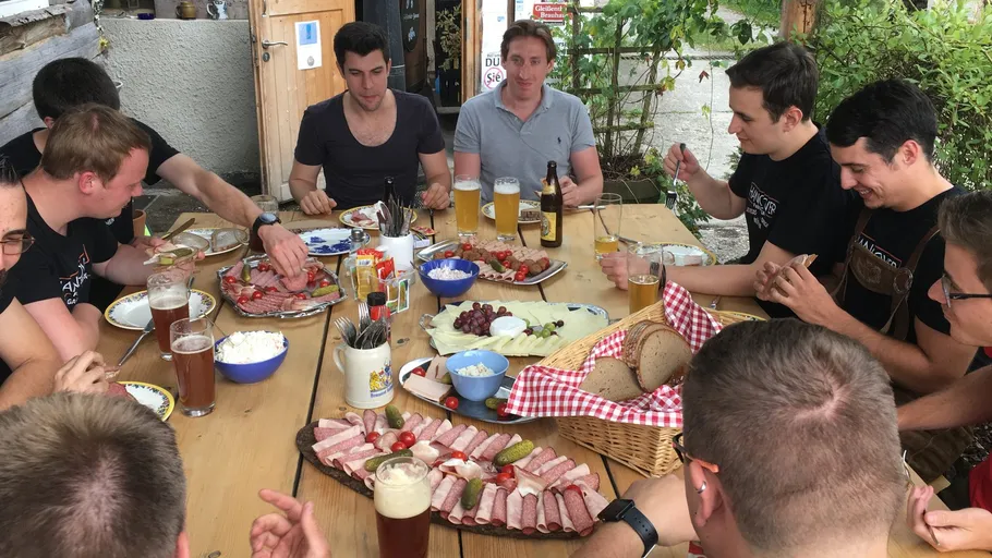 Men sharing food and drinks at outdoor table.