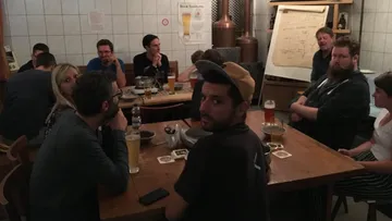 People gathered around tables in a brewery.