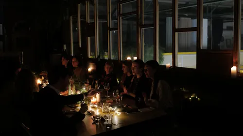 Menschen essen bei Kerzenlicht im dunklen Raum.
