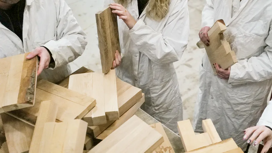 Personen in Laborkitteln mit Holzplanken drinnen.