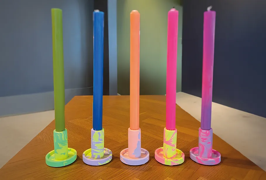 Fünf bunte Kerzen auf einem Holztisch.