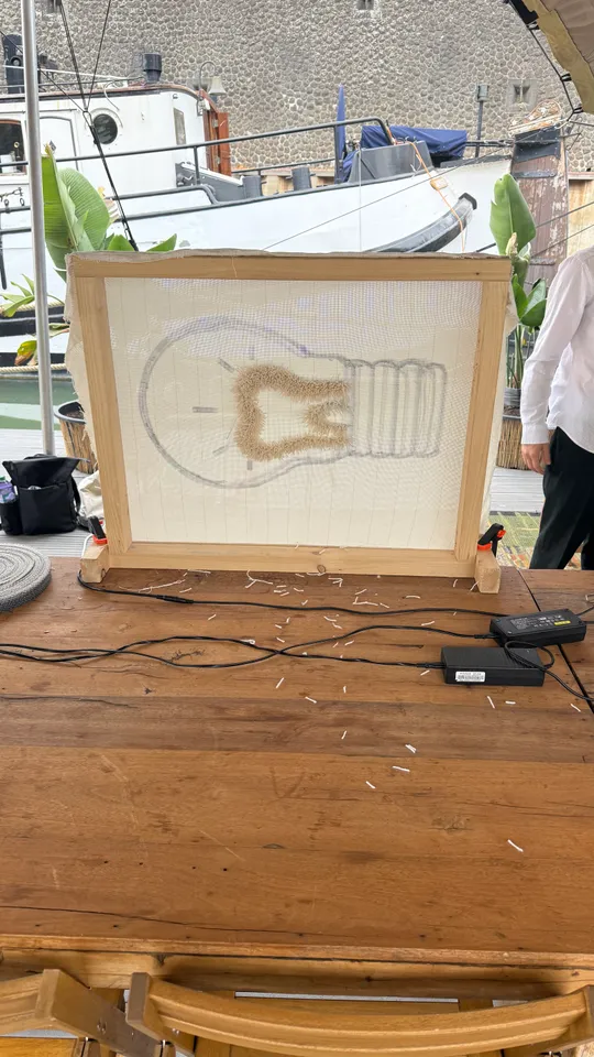 Framed lightbulb artwork on wooden table outside.