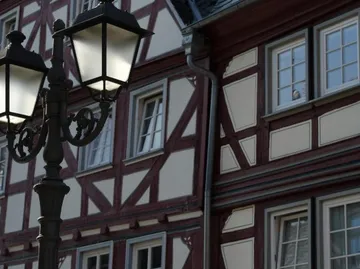 Lantern glows, stands next to a half-timbered house.