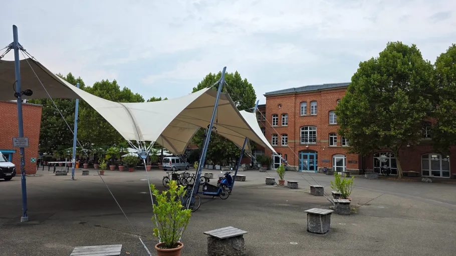 Hof mit Vordach und roten Ziegelgebäuden.