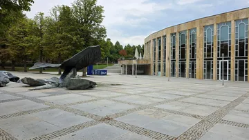 Whale sculpture in front of modern building.