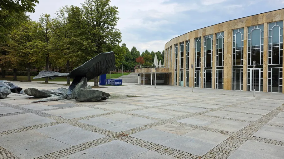 Whale sculpture in front of modern building.