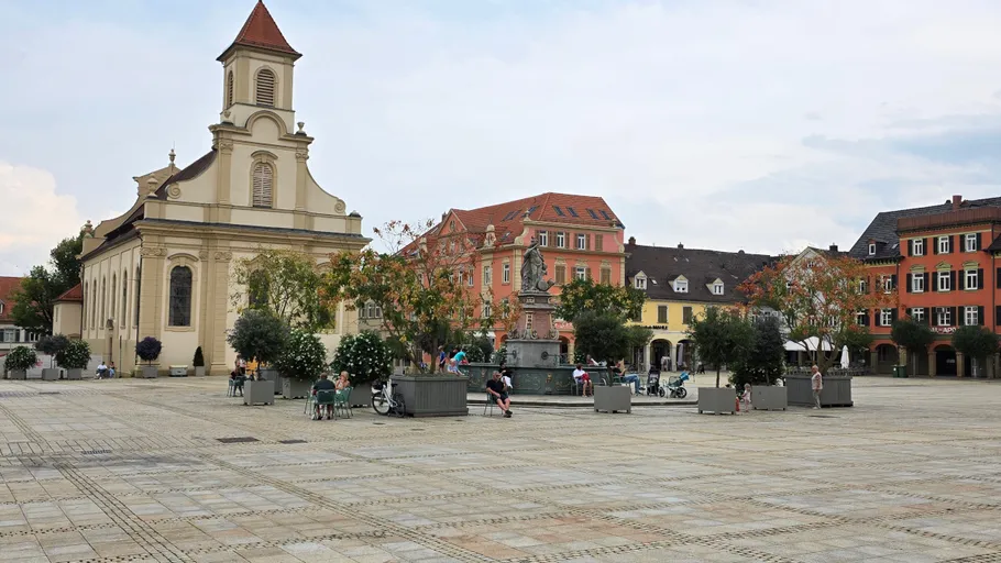 Quiet plaza with church and colorful buildings.