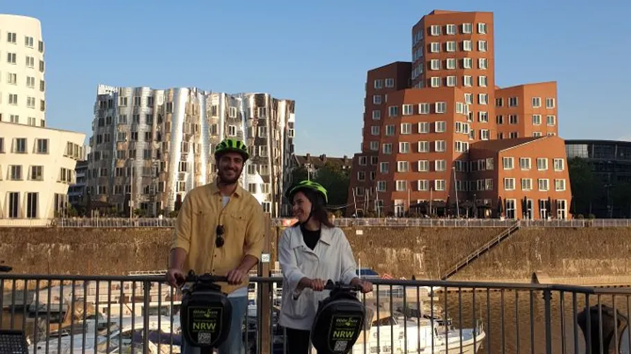 Zwei Personen auf Segways nahe modernen Gebäuden. Medienhafen