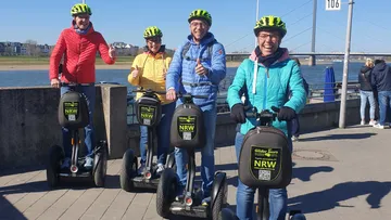 Four people on Segways near a river.