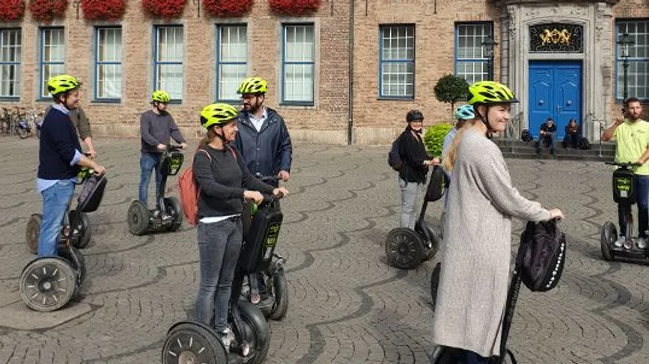 People ride Segways in a cobblestone plaza.