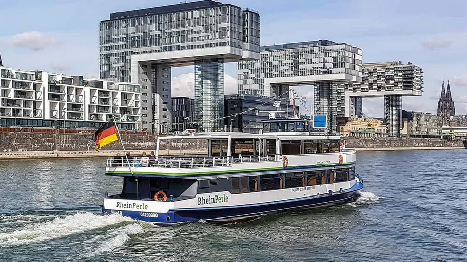 Boot segelt auf Fluss mit modernen Gebäuden in der Nähe.