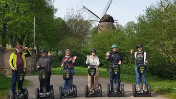 Six people on Segways near a windmill.