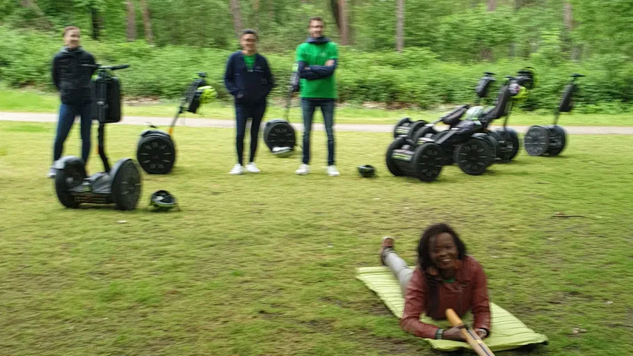 People with segways in a forest clearing.