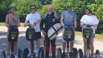 Fünf Personen auf Segways, eine im Mittelalterkostüm.