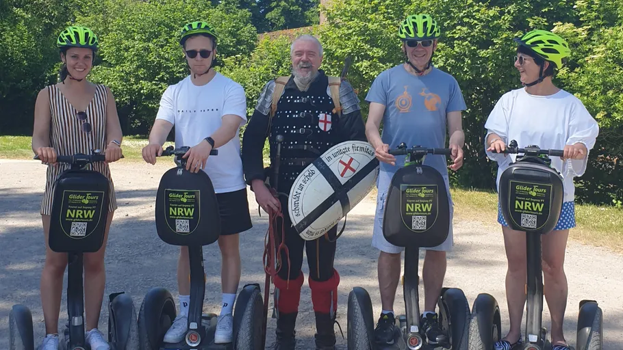 Five people on Segways, one in medieval costume.