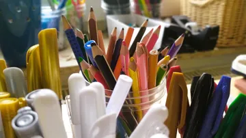 Colorful pencils in a cup on a desk.