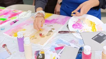 Person painting colorful art on canvas.