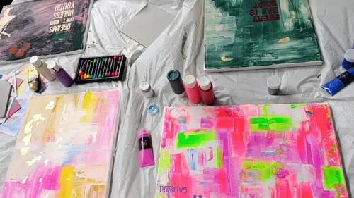 Abstrakte Gemälde und Kunstmaterialien auf Tisch.