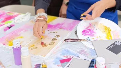 Hands painting on canvas with gold leaf.