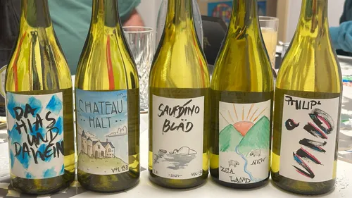 Five wine bottles with colorful labels displayed.