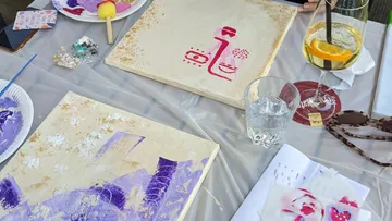 Kunstmaterialien und Gemälde auf einem Tisch.