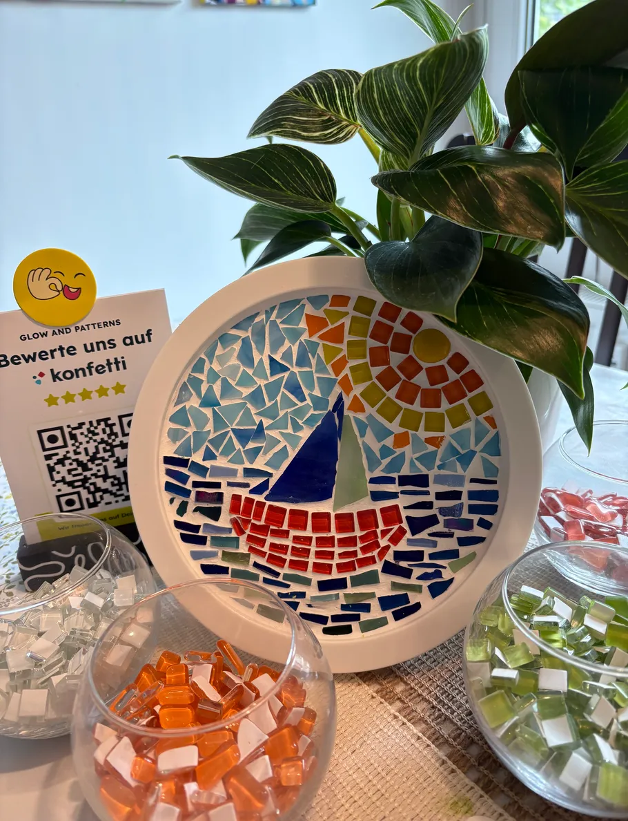 Mosaik eines Segelboots mit Pflanze daneben.