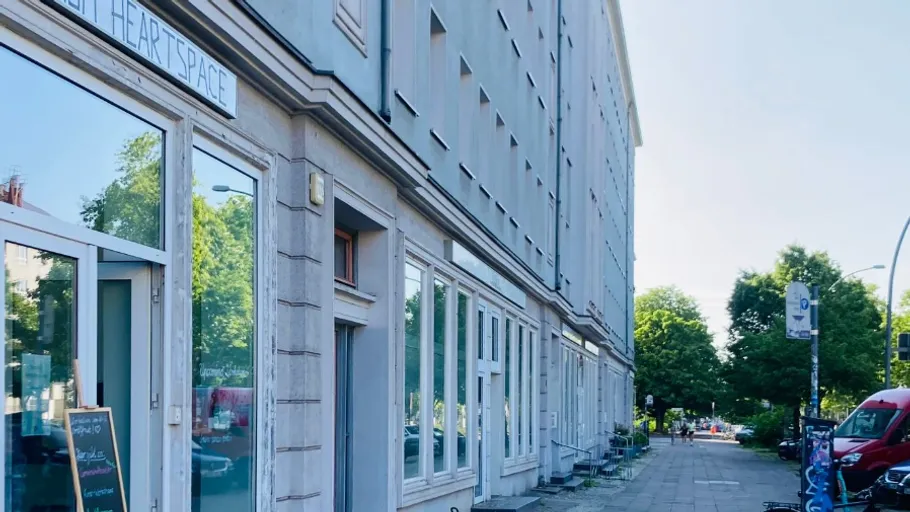 Building with storefront, street, and parked vehicles.