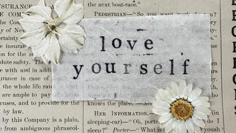 Text 'love yourself' mit weißen Blumen.