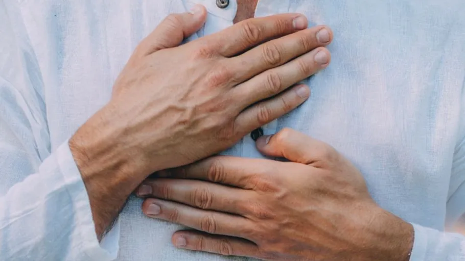 Person holding hands over chest, wearing white shirt.