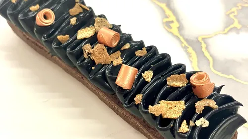Schokoladengebäck mit schwarzem Zuckerguss und Golddeko.
