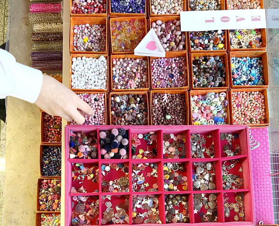 Hand selecting colorful beads in organized boxes.