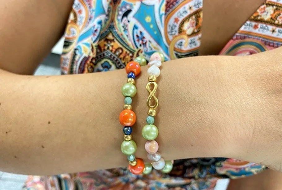 Beaded bracelets on wrist, colorful background.
