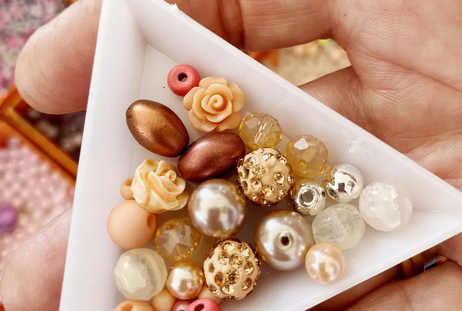 Assorted beads in hand-held triangular tray.