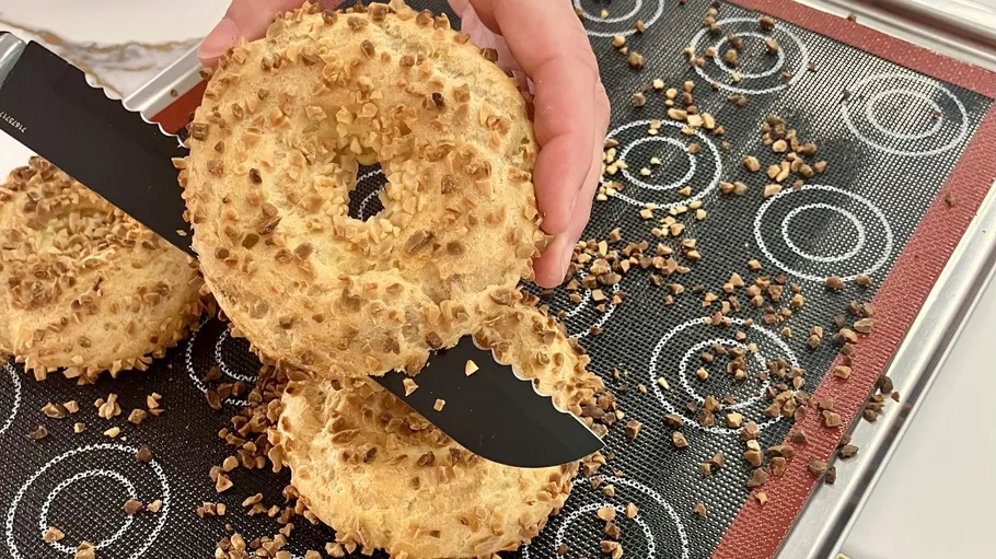 Geschnittener Bagel mit Nüssen auf Backmatte.