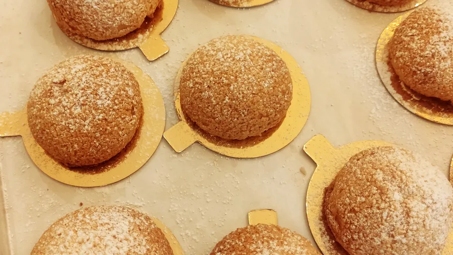 Gebäckbrötchen mit Puderzucker auf goldenen Unterlagen.