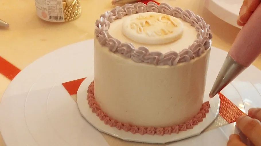 Person dekoriert runden Kuchen mit Glasur.