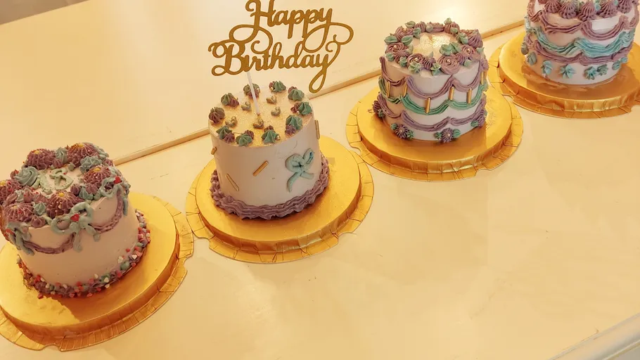 Vier dekorierte Kuchen mit 'Happy Birthday' Schild.