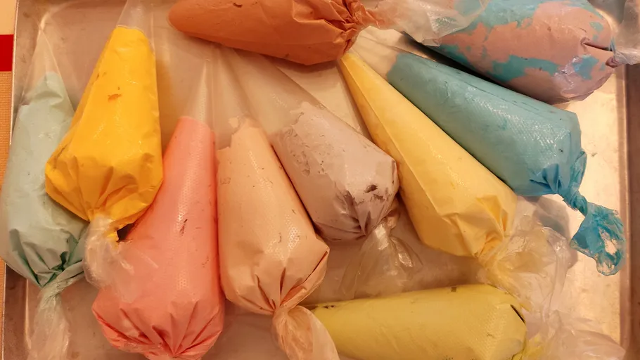 Colorful icing bags on a metal tray.