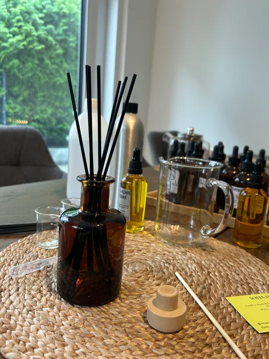Brauner Diffuser mit schwarzen Stäben auf Tisch.