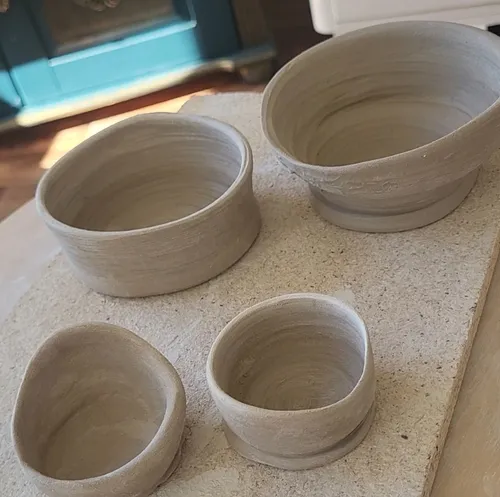 Clay bowls drying on a textured board.